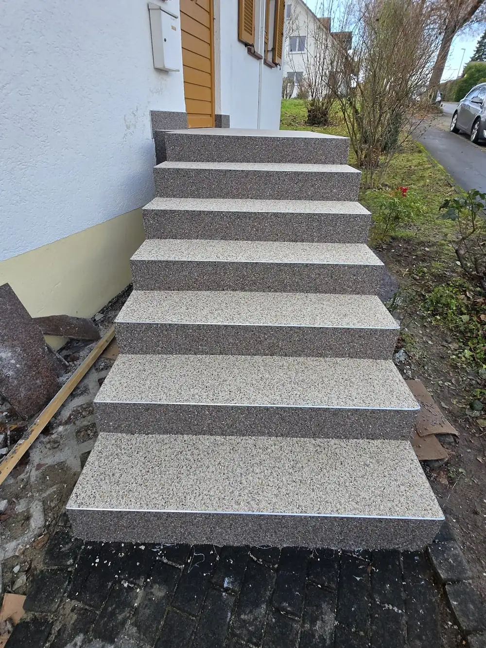 Nachher: Dunkle Granittreppe – abgedichtet und mit zweifarbigem Steinteppich belegt: helle Stufen, dunkle Kanten