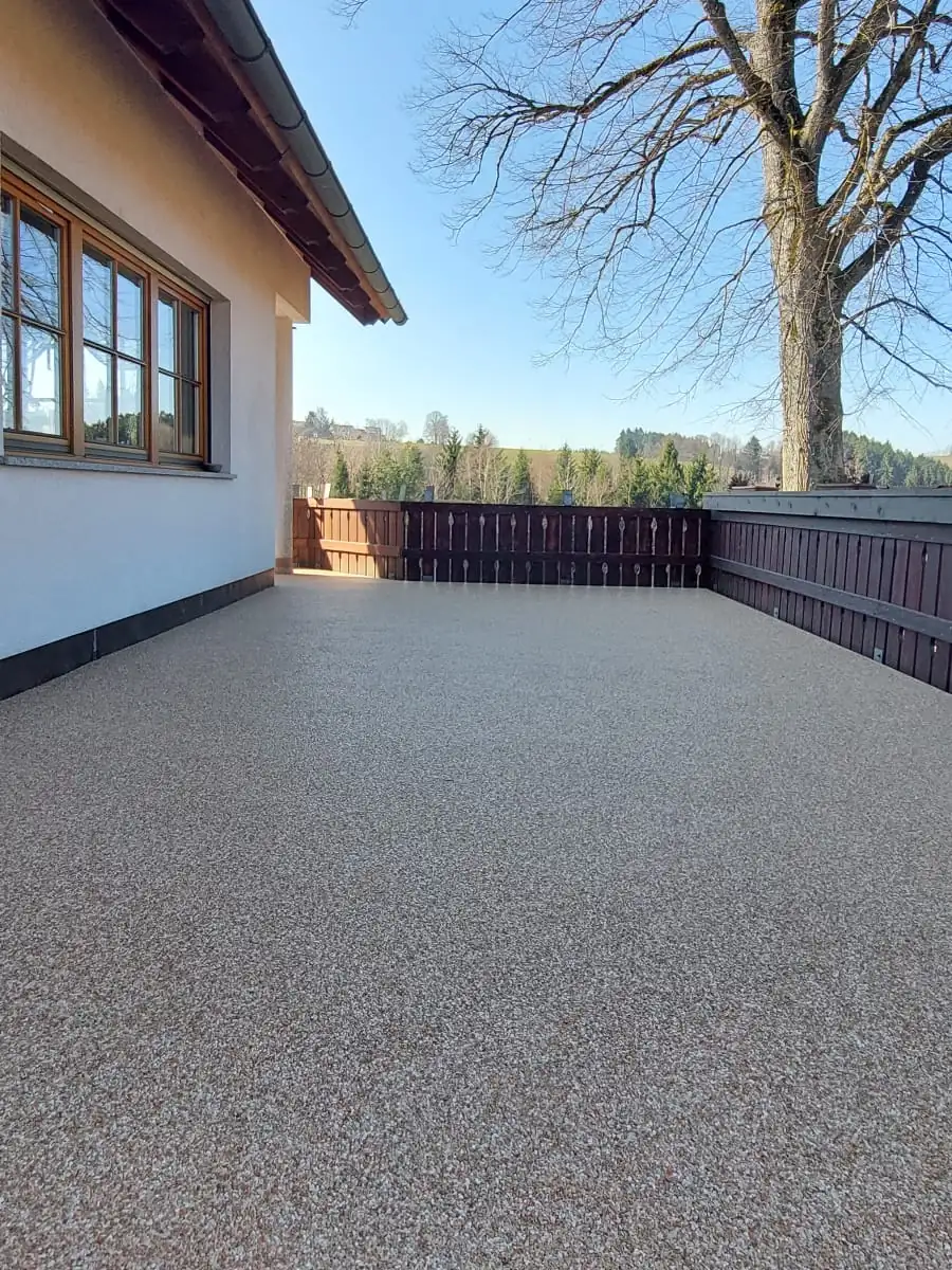 Nachher: Großer Betonbalkon mit Holzgeländer – abgedichtet und mit beigem Steinteppich belegt