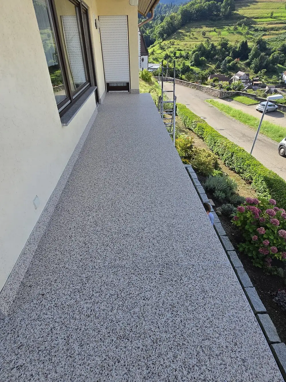 Nachher: Langer Balkon mit Blick in die Reben – alte Fliesen überarbeitet, abgedichtet und mit grauem Steinteppich belegt