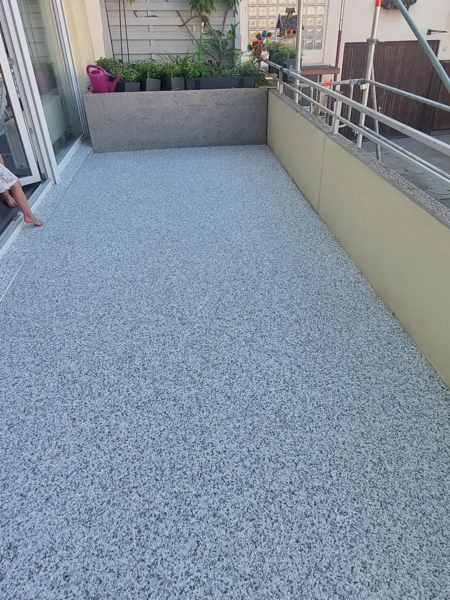 Nachher: Terracotta-Fliesen auf langem Balkon – ersetzt durch hellgrauen Steinteppich