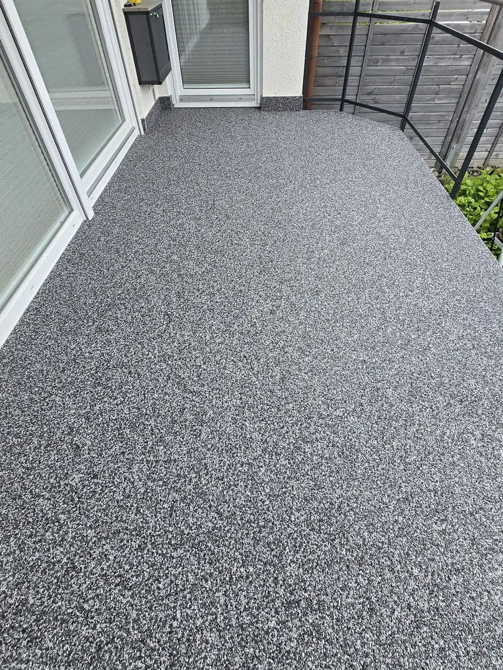 Balkon mit Steinteppich in Anthrazit-Mix vor bodentiefen Fenstern