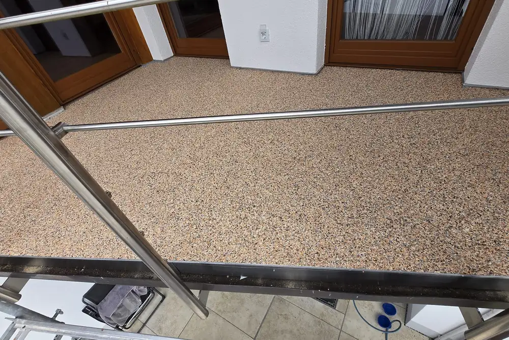 Balkon mit Steinteppich in Braun-Beige-Mischung und Edelstahlgeländer