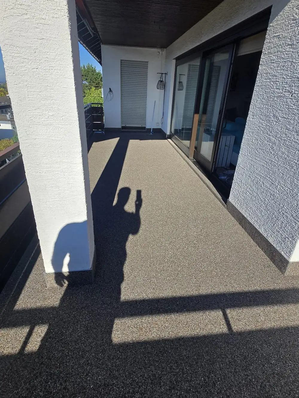 Überdachter Balkon mit dunklem Steinteppich