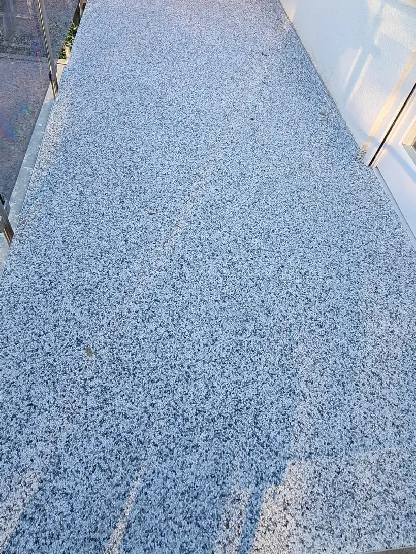 Balkon mit hellgrauem Steinteppich im Sonnenlicht