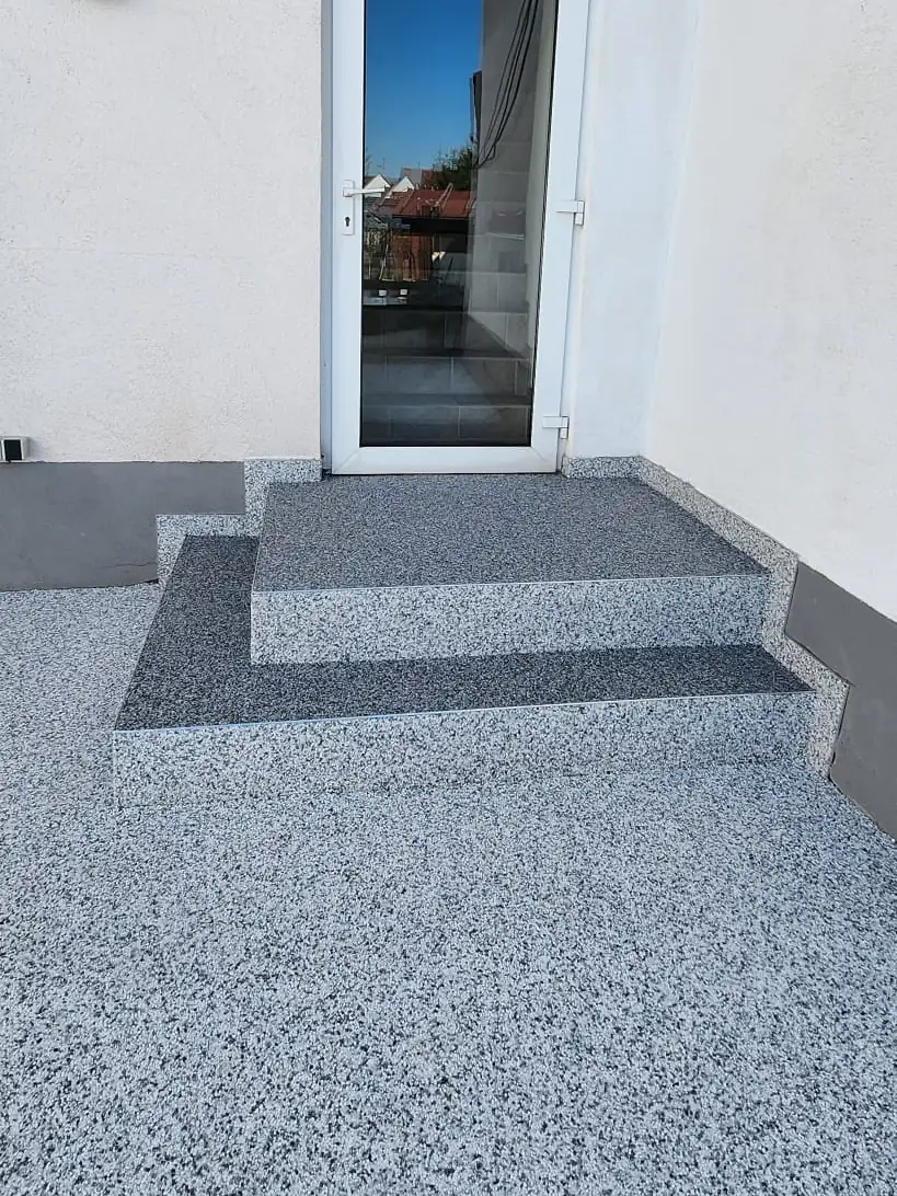 Nachher: Hauseingang mit kaputtem Podest – neu aufgebaut und mit Steinteppich belegt