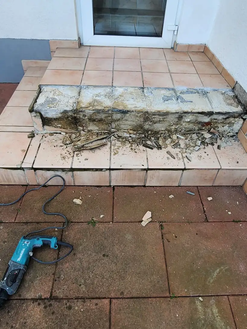 Vorher: Hauseingang mit kaputtem Podest – neu aufgebaut und mit Steinteppich belegt