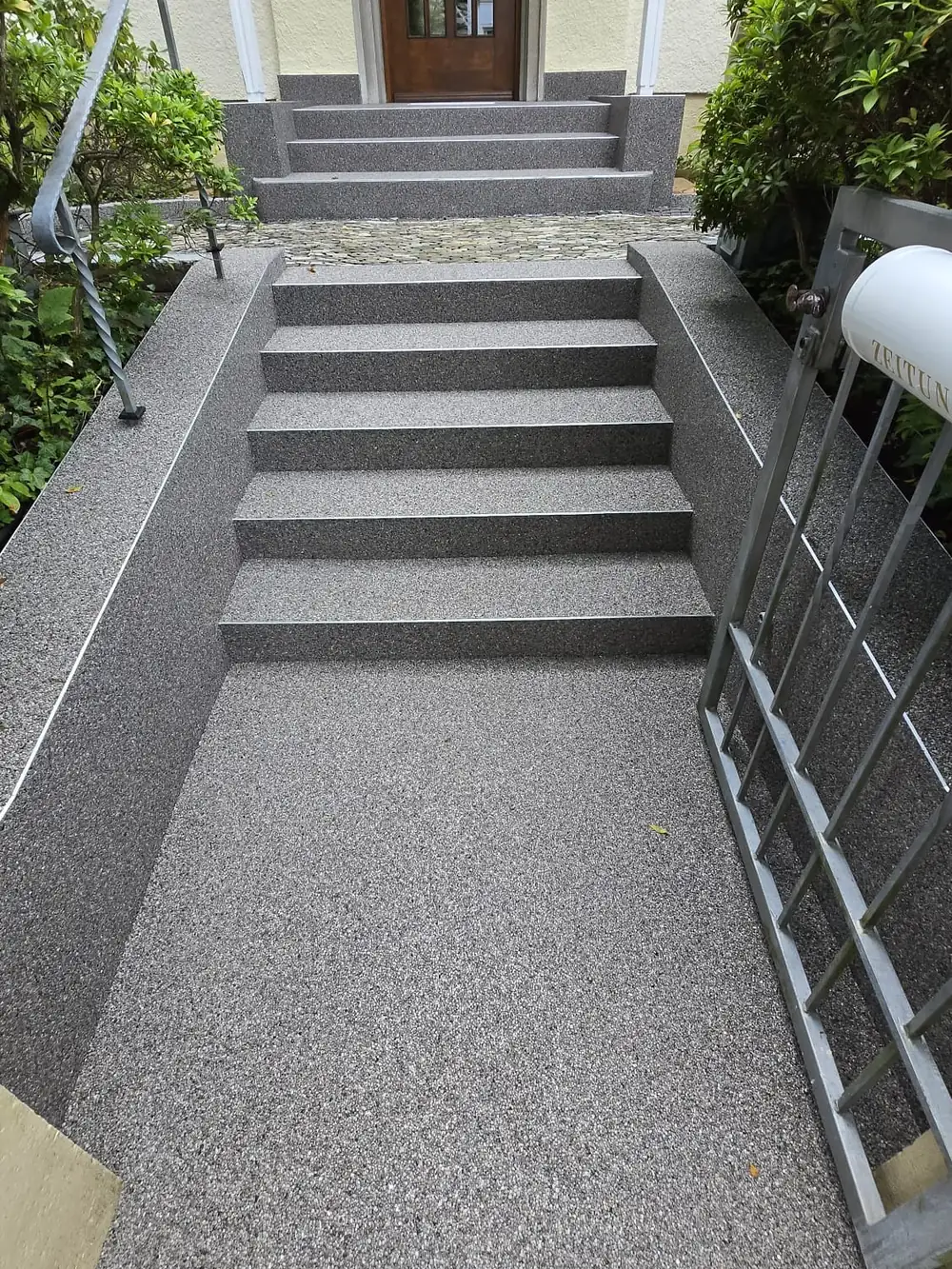 Eingangsbereich mit Treppe und Weg in sandfarbenem Steinteppich
